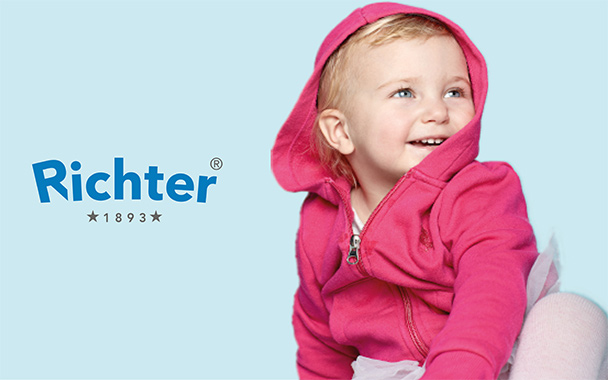 Blondes Kleinkind mit pinkem Zipper und Richter Marken Logo